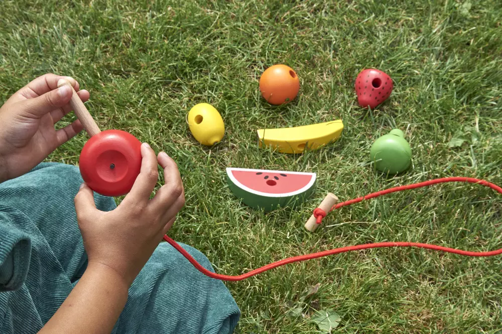 Zabawy związane z nawlekaniem owoców na sznurek to dobry trening koordynacji.